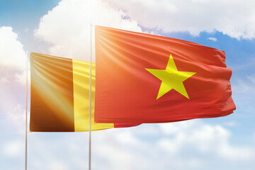 Sunny blue sky and flags of vietnam and belgium
