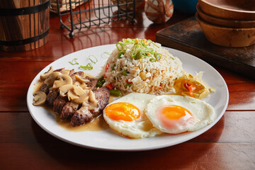 Brunch breakfast with beef, fried rice and eggs served in a dish isolated on wooden background side view