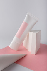 White cosmetics cream tube on pink background template, mock up, no brand. Face skin anti aging care. Concrete decor. Copy space.
