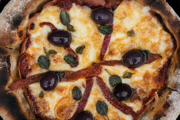Pizza background. Closeup view of a pizza with mozzarella cheese, grilled red bell peppers, ham, black olives and fresh oregano leaves.