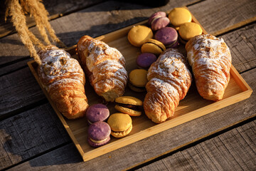 Picnic at the park. colored french macaroons or macarons yellow and violet and croissants on wooden tray on a hot summer day. Picnic lunch. selective focus. High quality photo