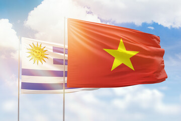 Sunny blue sky and flags of vietnam and uruguay