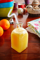 A jar of healthy fresh orange juice with straw isolated on wooden background side view