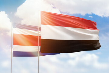 Sunny blue sky and flags of yemen and costa rica