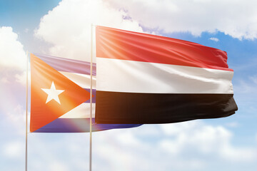 Sunny blue sky and flags of yemen and cuba