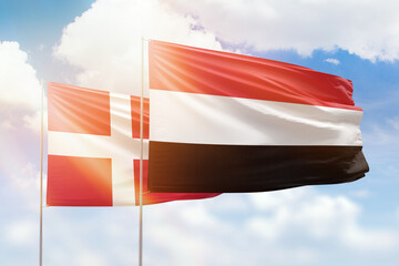 Sunny blue sky and flags of yemen and denmark
