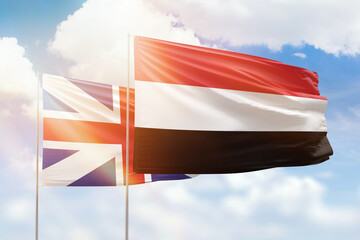 Sunny blue sky and flags of yemen and great britain