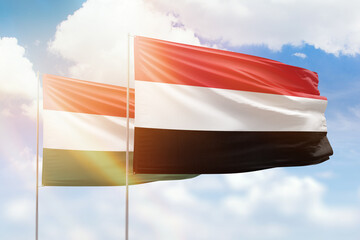 Sunny blue sky and flags of yemen and hungary