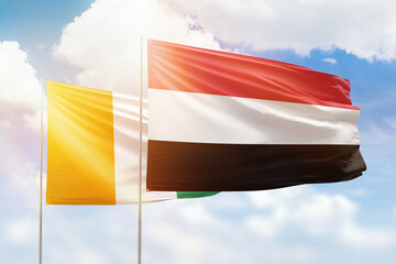 Sunny blue sky and flags of yemen and ivory coast