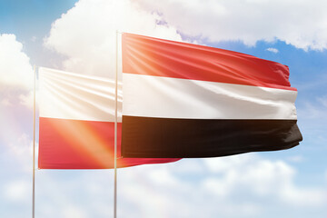 Sunny blue sky and flags of yemen and poland