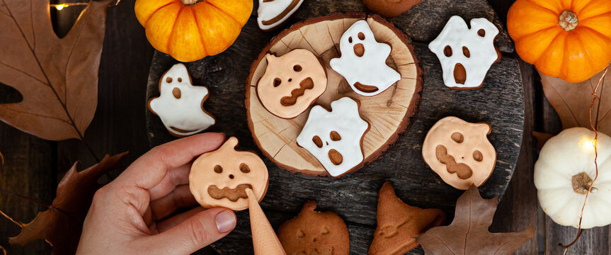 Homemade halloween holiday treats for kids. Gingerbread cookies on wooden board, decorated with pumpkins and autumn leaves. Top view. Banner