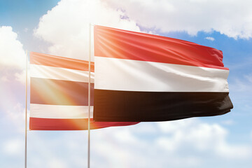 Sunny blue sky and flags of yemen and thailand