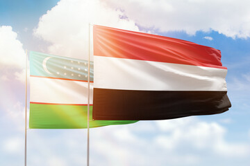 Sunny blue sky and flags of yemen and uzbekistan