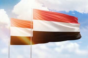 Sunny blue sky and flags of yemen and yemen