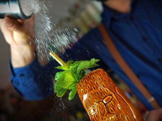 Delicious Tiki cocktail in trendy bar with bottle out of focus background and copy space vertical...