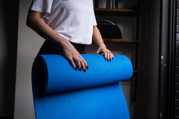 woman collecting blue yoga mat at home, home gym routines