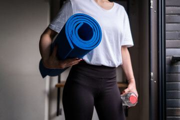 Fototapeta na wymiar young woman looking out window of modern house with yoga mat and pick, home gym routines