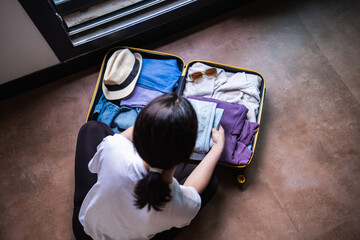 young and modern woman packing suitcase,preparing for vacation and spending time at home