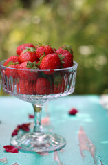 Strawberry in a glass bowl. summer fruit close up photo. Sunny day in the garden. 
