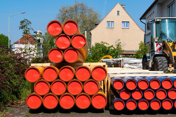 Construction site. Tractor and stack of orange-yellow and blue PVC conduit pipes.