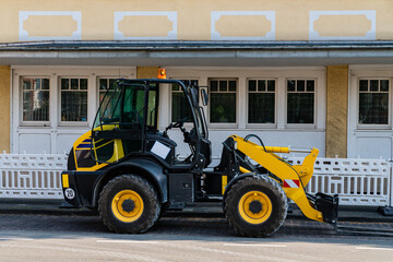 Yellow tractor on the road. Building on background.