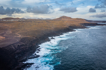 aerial view on volcano and mountains on coast with ocean waves on lanzarote