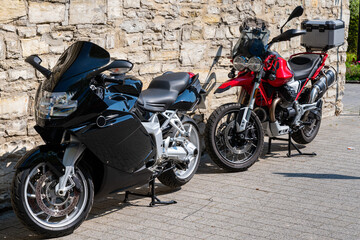 Two motorcycles standing against a stone wall.