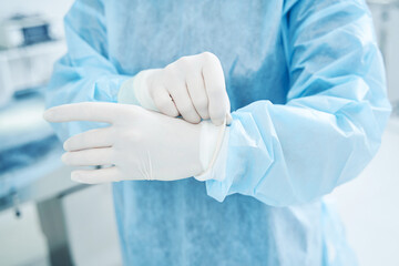 Unrecognized doctor in protective uniform preparing for surgery