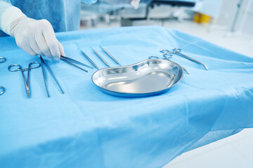 Medical worker grabbing sterile tools from the tray