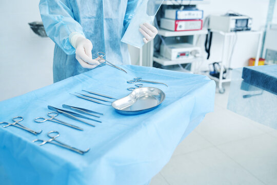 Doctor in surgical gown putting necessary tools into the tray