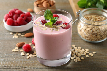 Glass of tasty raspberry smoothie with oatmeal and mint on wooden table