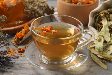 Freshly brewed tea and dried herbs on grey wooden table, closeup