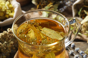 Freshly brewed tea and dried herbs on table, closeup