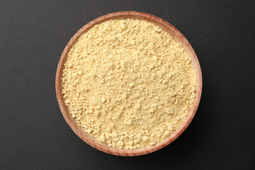 Wooden bowl with mustard powder on grey background, top view