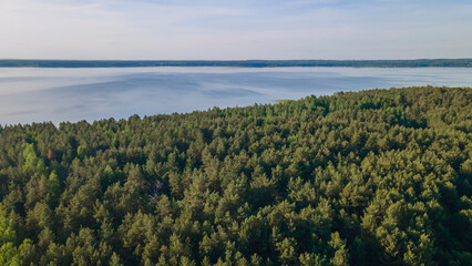 Aerial photo of forest on lakeside and water reservoir lake with sky reflection on water. Nature background.