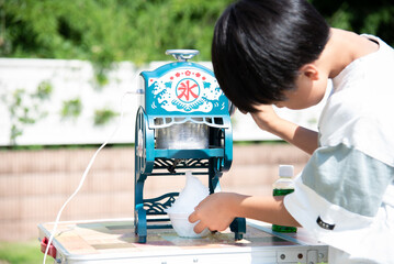 夏休みに庭でかき氷を作る小学生の男の子