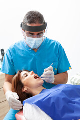 Male middle-aged dentist at his office with a female patient