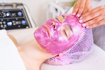Beautician applies a woman a therapeutic cream on her face.  Cosmetologist making  massage the skin...
