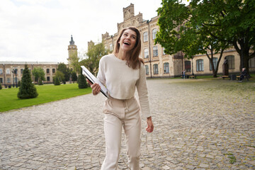 Fototapeta premium Happy woman with laptop standing on the street