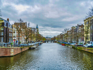 Fototapeta premium Dutch buildings and canal on a cloudy day in Amsterdam, Netherlands