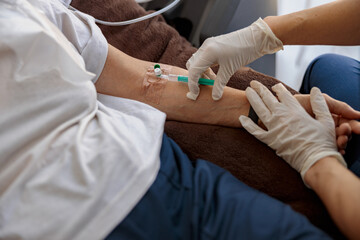 Nurse putting a drip in the arm of her patient in modern medical clinic. High quality photo