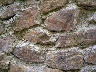 Ancient stonework. The stones are reinforced with old mortar. Uneven masonry ancient wall.