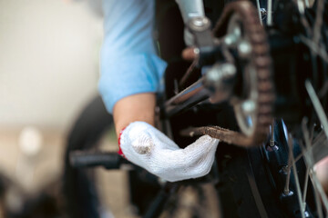 Portrait of man mechanic in garage or workshop inspecting classic motorcycle during the maintenance.