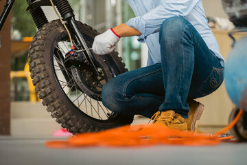 Obraz premium Portrait of man mechanic in garage or workshop inspecting classic motorcycle during the maintenance.