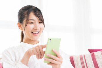部屋でスマホを見る女性
