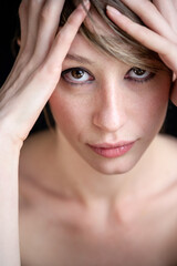 Fototapeta premium Strong eye contact from a female model in natural makeup. A close-up head and shoulder studio portrait of a beautiful young woman.