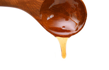 Honey dripping from a wooden honey dipper isolated on white background 