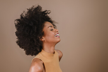 Side a smiling young Latin afro woman. Joy, positive and love. Beautiful african-style hair. Pastel...
