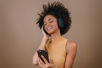 Beautiful Latin girl using her mobile phone. Listening music on headphones.