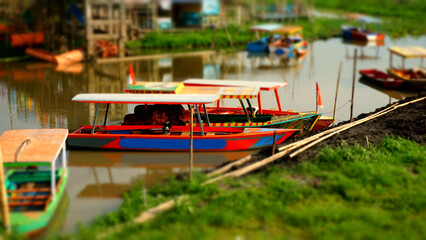 Fototapeta na wymiar View of the full-color boat on the lake with miniature tilt-shift effect